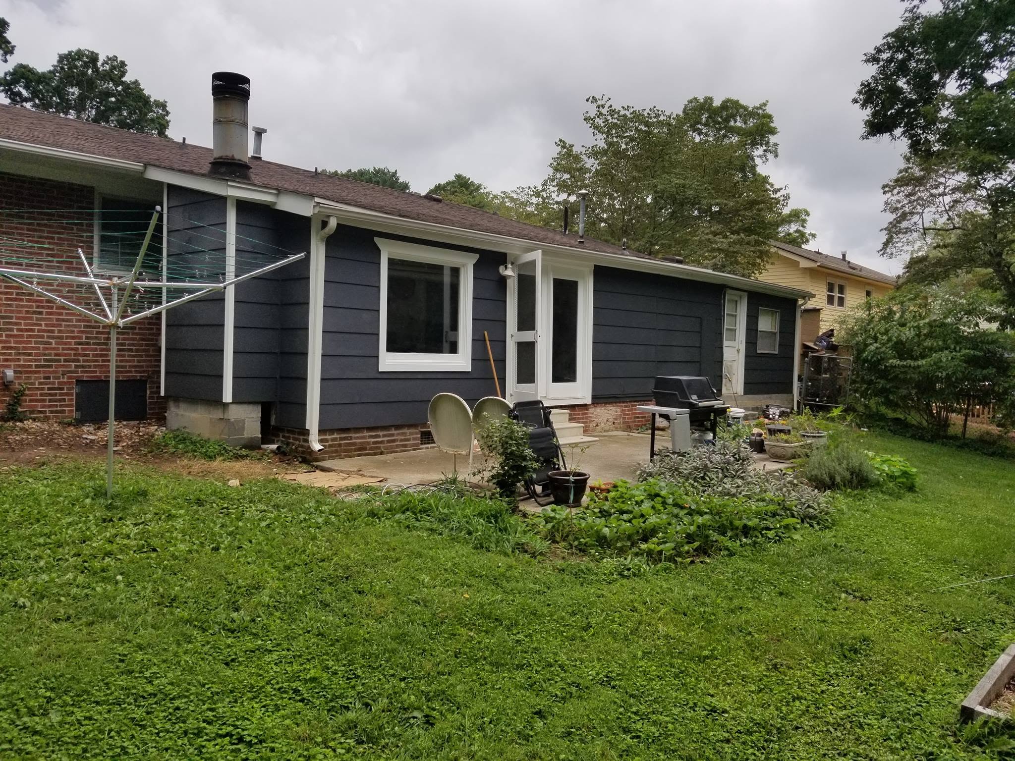 Rear elevation of renovated home with new dark siding, windows, and trim
