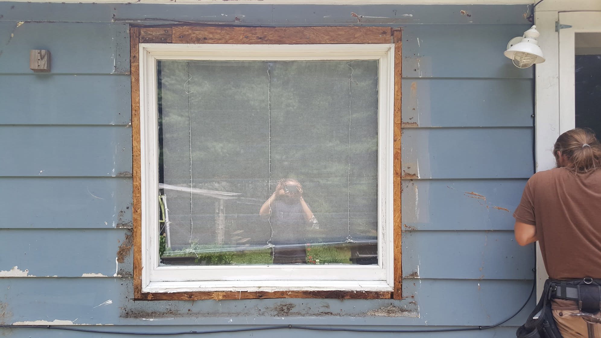 Weathered blue lap siding with peeling paint and exposed sheathing before renovation