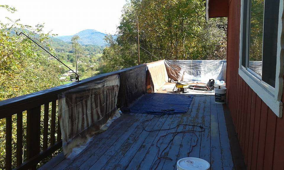 Weathered deck boards and railings prepped for refinishing with mountain view in background