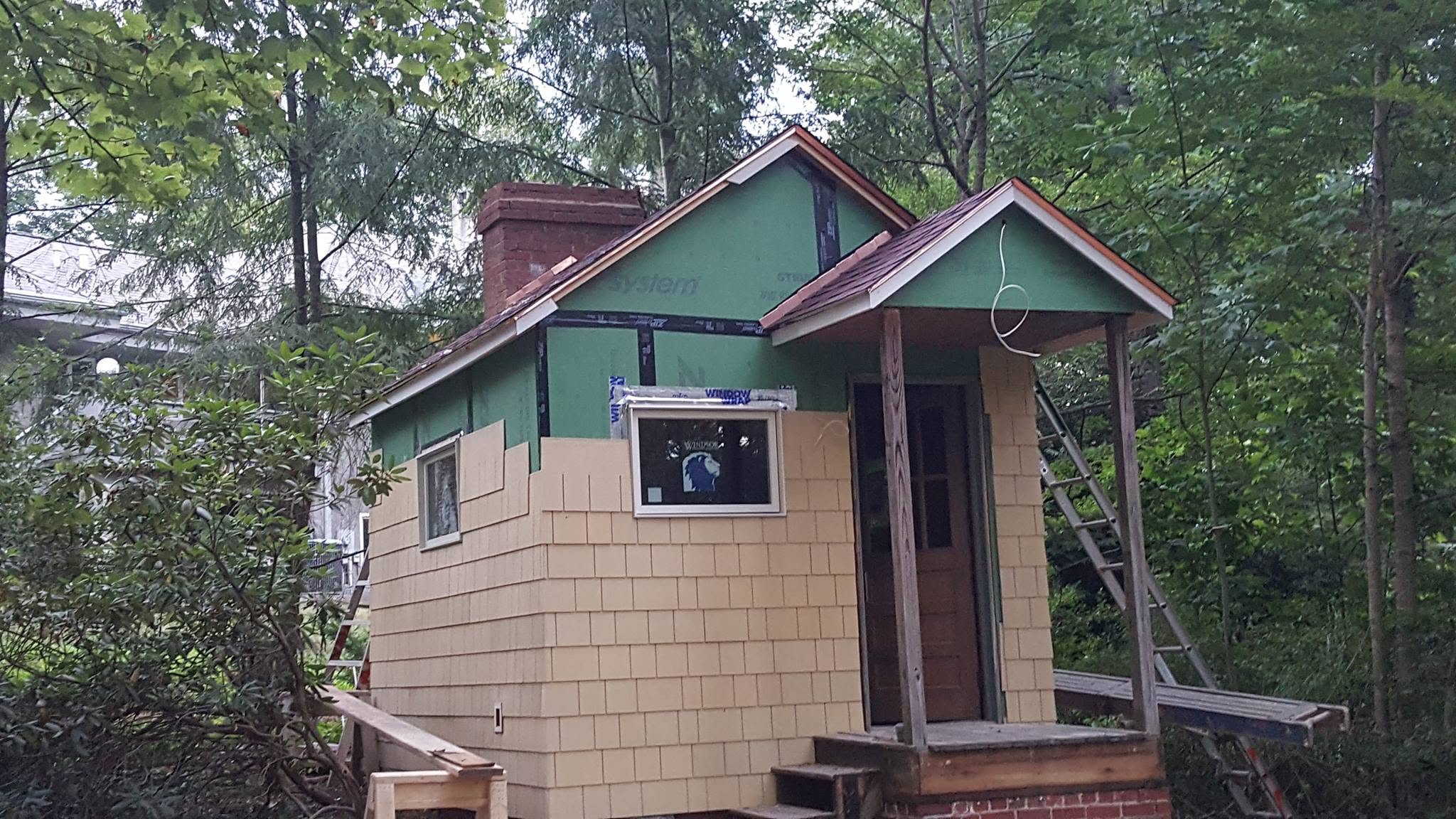 Small custom outbuilding under construction with cedar shake siding going on